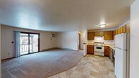 This single-floor unit offers a practical and functional layout with a seamless flow between the main living and kitchen areas. The open-concept living space features neutral carpet flooring that transitions into tile in the kitchen and entry areas, creating a clear delineation between zones. A wall-mounted air conditioning unit and baseboard heating provide year-round climate control, while a sliding door leads to an outdoor balcony, bringing in natural light and outdoor access.

The kitchen is well-equipped with warm oak cabinetry spanning both upper and lower sections, light countertops, and a full suite of appliances including an electric range, built-in microwave, dishwasher, and refrigerator. A single-basin sink sits beneath additional cabinet storage, and the tile flooring adds durability to the space.

The bedrooms are carpeted for comfort, with one featuring a ceiling fan with light fixture and a window overlooking outdoor greenery, while another includes a spacious walk-in closet with built-in shelving and rod storage. The full bathroom is finished with tile flooring, an oak vanity with a wide mirror, and a full tub-shower combination. Throughout the unit, warm wood-toned trim and doors provide a cohesive, classic aesthetic.