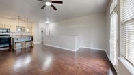 Located at 22202 Estate Hill Dr in San Antonio, TX, this two-story, three-bedroom, two-bathroom home offers a well-organized layout across two levels. The main level hosts the combined kitchen and living area, where rich hardwood-style flooring runs throughout. The kitchen is equipped with white cabinetry, granite-style countertops, black appliances including a refrigerator, range, microwave, and dishwasher, and a peninsula with pendant lighting that doubles as a breakfast bar. A ceiling fan anchors the open living area, which flows seamlessly from the kitchen. The upper level contains all three bedrooms, each finished with plush carpet and ceiling fans. The spacious primary bedroom includes a walk-in closet outfitted with wire shelving. Additional bedrooms feature natural light from large windows and dedicated closet space. Both bathrooms are finished with hardwood-style flooring, gray cabinetry with granite-style countertops, and tub-shower combinations with tiled surrounds. A hallway connects the upper-level rooms, which are also served by a staircase. The home also features a private balcony offering open views of the surrounding neighborhood and Texas Hill Country skyline, providing a pleasant outdoor retreat.