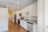 Located at 7105 Hall Rd in Union City, GA, this one-bedroom, one-bathroom unit offers a well-designed single-floor layout that maximizes every square foot. The open-concept living, dining, and kitchen area serves as the heart of the home, bathed in natural light from large windows. The kitchen is outfitted with crisp white shaker cabinetry, granite countertops, a stainless steel refrigerator, range, microwave, and dishwasher, all complemented by warm hardwood-style flooring that extends throughout the unit. A stylish barn door adds a functional and modern architectural touch along the main corridor. The hallway connects seamlessly to the bedroom, which offers a comfortable footprint, neutral toned walls, and a window with views of the surrounding area. The full bathroom features a white shaker vanity with granite countertops, a large mirror, and a tub-shower combination. Additional conveniences include a dedicated laundry area, a utility room, and three closets providing ample storage. Recessed lighting throughout enhances the clean, contemporary aesthetic. The unit presents a cohesive, move-in-ready interior with consistent finishes across all rooms.