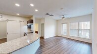 Located at 201 Wildwood Blvd in Forney, TX, this well-appointed 2-bedroom, 2-bathroom residence offers a thoughtfully designed single-floor layout. The open-concept living and kitchen area serves as the heart of the home, featuring rich dark-wood cabinetry, granite countertops with a curved breakfast bar, stainless steel appliances including a refrigerator with ice maker, and recessed lighting throughout. Wood-look flooring flows seamlessly across the main living space, while a ceiling fan adds both style and function. A sliding barn door adds a modern touch near the kitchen entry. Natural light fills the living area through large windows with exterior views, and a glass-paneled door provides additional brightness. The spacious primary bedroom features plush carpet, a ceiling fan, and a generous window. The second bedroom also offers carpet flooring, a ceiling fan, and ample natural light. Both bathrooms are finished with dark wood vanities, white countertops, and matching wood-look flooring. A dedicated laundry area with washer and dryer hookups adds everyday convenience. Two closets provide practical storage throughout. The space combines clean, neutral tones with quality finishes for a comfortable and functional living environment.