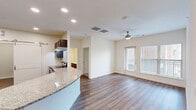 Located at 201 Wildwood Blvd in Forney, TX, this well-appointed 2-bedroom, 2-bathroom residence offers a thoughtfully designed single-floor layout. The open-concept living and kitchen area serves as the heart of the home, featuring rich dark-wood cabinetry, granite countertops with a curved breakfast bar, stainless steel appliances including a refrigerator with ice maker, and recessed lighting throughout. Wood-look flooring flows seamlessly across the main living space, while a ceiling fan adds both style and function. A sliding barn door adds a modern touch near the kitchen entry. Natural light fills the living area through large windows with exterior views, and a glass-paneled door provides additional brightness. The spacious primary bedroom features plush carpet, a ceiling fan, and a generous window. The second bedroom also offers carpet flooring, a ceiling fan, and ample natural light. Both bathrooms are finished with dark wood vanities, white countertops, and matching wood-look flooring. A dedicated laundry area with washer and dryer hookups adds everyday convenience. Two closets provide practical storage throughout. The space combines clean, neutral tones with quality finishes for a comfortable and functional living environment.