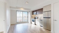 Located in Ottawa's vibrant Centretown neighbourhood, this modern 2-bedroom, 1-bathroom unit at 46 Flora St offers a thoughtfully designed open-concept layout with a clean, contemporary aesthetic throughout. Light wood-look flooring flows seamlessly across the entire unit, complementing the crisp white walls and adding warmth to the space.

The combined living, dining, and kitchen area forms the heart of the unit. The kitchen is outfitted with a full suite of stainless steel appliances — including a refrigerator, electric range, microwave, and dishwasher — paired with two-tone cabinetry featuring white lower cabinets and rich dark upper cabinets. A large sliding glass door floods the living area with natural light and frames sweeping city views.

Both bedrooms are bright and well-proportioned, with large windows offering elevated views of the Ottawa skyline and surrounding cityscape. Each room includes closet storage and benefits from abundant natural light. Three closets in total provide ample storage throughout the unit.

The bathroom is finished in neutral wood-look tile, featuring a vessel sink atop a light wood vanity, a large mirror, and a glass-enclosed walk-in shower. In-unit laundry adds everyday convenience. The overall ambiance is clean, modern, and move-in ready.