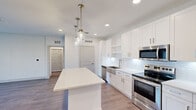 This thoughtfully designed 2-bedroom, 2-bathroom residence is laid out on a single floor, offering a clean, modern aesthetic throughout. The open-concept kitchen and living area serves as the heart of the home, featuring a striking white kitchen with shaker-style cabinetry, a subway tile backsplash, stainless steel appliances including a range, microwave, dishwasher, and refrigerator, and a spacious center island illuminated by elegant glass pendant lights. Wood-style flooring flows seamlessly throughout the entire residence, adding warmth and continuity. The living room is generously sized, featuring a ceiling fan and large sliding glass doors fitted with vertical blinds that open to an outdoor view, filling the space with natural light. Both bedrooms are well-proportioned and bright, each with large windows overlooking the surrounding neighborhood. The primary bedroom offers a comfortable, spacious layout. The two bathrooms are finished in a crisp, clean style — one features a tiled tub-shower combo, while the other includes a walk-in tiled shower, a white vanity with a rectangular sink, and a large framed mirror. A dedicated closet provides additional storage. The overall ambiance is bright, airy, and move-in ready.