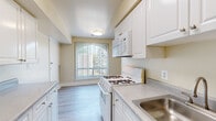 Located at 799 Quince Orchard Blvd in Gaithersburg, MD, this single-floor home offers four bedrooms and two bathrooms within a well-organized layout. The interior is finished with neutral warm beige walls and clean white trim throughout, creating a bright and cohesive atmosphere. Soft carpeting runs through the living areas and bedrooms, while the kitchen and bathrooms feature easy-care hard-surface flooring.

The galley-style kitchen is thoughtfully designed with white cabinetry, gray laminate countertops, white gas appliances including a range, microwave, and refrigerator, and a window that draws in natural light. The layout maximizes storage and counter space efficiently.

The generously sized primary bedroom is one of the standout features of the home, offering ample room to furnish comfortably. It includes a walk-in closet with dual hanging rods and shelving. Three additional bedrooms provide flexible space suitable for sleeping, working, or other uses, each with carpeted floors and access to closet storage.

Both bathrooms are clean and functional; one features a full tub-shower combo with white tile surround, while the second offers light wood-tone flooring. Two hallways connect the rooms, enhancing flow throughout the home. A ceiling fan is visible in the living area, adding comfort year-round.