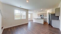 Located on Poplar Road in Newnan, Georgia, this two-story home presents a clean, modern interior with consistent dark hardwood-style flooring and crisp white walls throughout. The main level centers around an open-concept living and kitchen area, where natural light streams in through large windows fitted with horizontal blinds. The kitchen is well-appointed with gray shaker-style cabinetry, granite-look countertops, stainless steel appliances including a range, microwave, and refrigerator, and a central island that provides additional prep and seating space. The living area flows seamlessly from the kitchen, creating a practical and connected layout ideal for everyday living.

A dedicated laundry room on the main level houses a full-size washer and dryer with wire shelving above for additional storage. A full bathroom on this floor features tile flooring, a vanity with a white countertop, and a tub-shower combination. The staircase leads to the upper level, where a hallway connects multiple rooms, including a spacious walk-in closet outfitted with wire shelving systems and hardwood-style flooring. Bedrooms on this level feature neutral walls, dark flooring, and windows providing natural light and exterior views. The upper-level bathroom mirrors the clean, functional aesthetic found throughout the home.