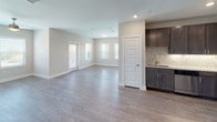 Located at 1305 Ridge Rd in Rockwall, Texas, this single-story unit offers a contemporary design with consistent, high-quality finishes throughout. Wood-style plank flooring runs continuously across all rooms, complementing the neutral gray and beige tones on the walls and contributing to a clean, cohesive aesthetic.

The kitchen is well-appointed with dark espresso cabinetry, granite-look countertops, a decorative mosaic tile backsplash, and a full suite of stainless steel appliances, including a refrigerator, range, microwave, and dishwasher. The open-concept living and dining area is generously sized, filled with natural light from multiple windows, and flows seamlessly from the kitchen.

The bedrooms are spacious, each featuring ceiling fans with light fixtures, windows with horizontal blinds, and closet storage. The primary bedroom connects to an en-suite bathroom with a dual-sink vanity topped with granite-style counters, dark cabinetry, a soaking tub, and a walk-in closet with built-in shelving. A secondary bathroom offers a tub-shower combination with tiled surround. Five-panel white interior doors and clean white trim are consistent throughout, reinforcing the modern, move-in-ready character of the space.