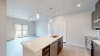 This well-appointed two-bedroom, two-bathroom single-story residence in Corinth, TX offers a thoughtfully designed open-concept layout that seamlessly connects the kitchen, dining, and living areas. The kitchen is a standout feature, anchored by a large center island with a white quartz countertop, an undermount sink, and dark espresso cabinetry that contrasts beautifully with light wood-look flooring. Stainless steel appliances, including a range, microwave, and refrigerator, are complemented by a subway tile backsplash and elegant pendant lighting overhead. The living area flows naturally toward sliding glass doors that open onto a private patio, filling the space with natural light. Both bedrooms are carpeted for comfort, each equipped with a ceiling fan and ample closet space. The primary bedroom is generously sized, while the second bedroom features a large window with outdoor views. The two bathrooms are finished with dark cabinetry, white countertops, and tub-shower combinations with clean white subway tile surrounds. A dedicated laundry area and multiple closets throughout add everyday convenience. The neutral color palette and modern finishes create a bright, cohesive ambiance throughout the entire residence.