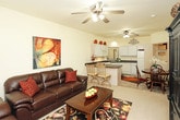 This single-story residence offers a comfortable and functional layout across several well-defined living spaces. The living room serves as the heart of the home, featuring vaulted ceilings, a ceiling fan, and a window that brings in natural light and outdoor views. The space is generously sized to accommodate full seating arrangements.

The kitchen is efficiently designed with white cabinetry, dark countertops, tile flooring, and a full suite of white appliances including a range, dishwasher, and refrigerator. A pass-through window connects the kitchen visually to the dining area, enhancing the open feel between spaces.

The dining area accommodates a round table with seating for four and benefits from elevated ceilings. A notable convenience feature is the in-unit laundry closet, located adjacent to the dining space and housing a full-size washer and dryer.

The bedroom offers carpeted flooring, a ceiling fan with light fixture, and a window overlooking the exterior. It provides ample space for a queen-sized bed and additional furniture.

The bathroom includes tile flooring, a shower-tub combination, a vanity with under-sink storage, and a wall-mounted mirror with overhead lighting. Flanking closets in the hallway provide additional storage just outside the bathroom entrance.