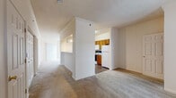 Located at 3390 Clear Water Dr in Hamilton, Ohio, this single-floor residence offers a thoughtfully arranged layout designed for comfortable everyday living. The open living area features neutral-toned wall-to-wall carpeting and is connected to a pass-through kitchen via a half-wall opening with track lighting above, creating a sense of openness between the two spaces. The galley-style kitchen is equipped with warm wood cabinetry, laminate countertops, a full suite of white appliances including a refrigerator, range, microwave, and dishwasher, and durable hardwood-style flooring. A carpeted hallway with built-in closets connects the living areas to the private quarters. The bedrooms are generously sized with plush carpeting, large windows that bring in natural light, and ample closet space, including a built-in shelved closet in one room. Two bathrooms serve the unit, each featuring rich wood-toned vanities with stone-look countertops, undermount sinks, mirrors, and hardwood-style flooring. Textured ceilings throughout add character, while the neutral color palette and clean lines create a bright, welcoming ambiance throughout the home.