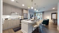 This single-floor residence showcases a thoughtfully designed open-concept layout that seamlessly connects the kitchen, dining, and living areas. The kitchen is a standout feature, equipped with stainless steel appliances including a gas cooktop, double wall ovens, a built-in wine refrigerator, and a full-size refrigerator. Light wood-grain cabinetry pairs with a striking marble-style tile backsplash and crisp white quartz countertops. A central island with seating for multiple guests serves as both a functional workspace and a casual dining hub, illuminated by a trio of modern pendant lights overhead. Rich hardwood flooring flows throughout the main living areas, anchoring the contemporary aesthetic.

The living area offers a relaxed yet refined atmosphere, accented by bold artwork and warm, curated décor. The bedroom features a dramatic dark accent wall, bold monochromatic artwork, and a large window that invites natural light and outdoor views.

Bathrooms are finished with large-format tile, including a full bath with a glass-enclosed walk-in shower and a soaking tub, and a half bath with a wood-grain vanity and gold-toned hardware. A dedicated laundry area with an in-unit washer adds everyday convenience. The overall ambiance is modern, clean, and cohesive.