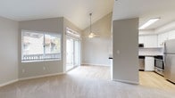 This single-floor residence at 8044 Pocket Rd in Sacramento's Pocket neighborhood offers a well-designed layout with a bright, open feel throughout. The living area is a standout, featuring dramatic vaulted ceilings with a ceiling fan and sliding glass doors that open to an outdoor balcony, flooding the space with natural light and providing views of the surrounding neighborhood. Soft carpet flooring adds warmth to the living and bedroom areas, while light hardwood-style flooring flows through the kitchen and bathrooms.

The kitchen is thoughtfully updated with crisp white shaker cabinetry, dark countertops, a herringbone tile backsplash, and a full suite of stainless steel appliances including a refrigerator, dishwasher, microwave, and range. The clean, modern aesthetic carries into the bathrooms, which feature white cabinetry, dark countertops, wide mirrors, and contemporary light fixtures.

The bedrooms are generously sized, with neutral tones and carpeted floors. One bedroom benefits from vaulted ceilings, adding an airy sense of volume. The overall color palette throughout the home is composed of soft grays and warm whites, creating a clean, neutral, and move-in-ready atmosphere ideal for a variety of living styles.
