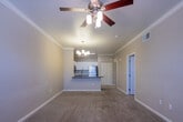 This single-floor residence offers a thoughtfully designed layout that balances comfort and functionality. The open-concept living and dining area is generously proportioned, featuring warm neutral-toned walls, plush wall-to-wall carpeting, crown molding, and an elegant chandelier that anchors the space. Large windows allow natural light to flow freely, creating a bright and welcoming atmosphere. A dedicated entry area with wood-look flooring provides a smooth transition into the main living space.

The kitchen is a standout feature, showcasing white shaker-style cabinetry, a classic subway tile backsplash, and dark quartz countertops that extend to a peninsula with bar-style seating. Stainless steel appliances — including a refrigerator, range, microwave, and dishwasher — add a modern, polished touch. Wood-look flooring runs throughout the kitchen, complementing the overall design.

The bedrooms are comfortable and well-sized, each finished with soft carpeting and neutral walls. One bedroom benefits from a large window offering views of surrounding greenery, while a chandelier-style light fixture adds a refined touch. The bathroom is clean and functional, featuring wood-look flooring, a tiled tub-shower combination, a vanity with dark countertops, and brushed nickel hardware throughout.
