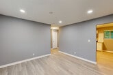 This single-floor home offers a practical and well-designed layout, accommodating four bedrooms, two bathrooms, a living room, and a kitchen within a comfortable footprint. The interior is finished with a consistent, modern aesthetic featuring cool grey walls, crisp white trim, and light-toned luxury vinyl plank flooring that flows through the main living areas, complemented by plush carpet in the bedrooms.

The kitchen is well-equipped, featuring white cabinetry with granite-look countertops, a stainless steel appliance suite including a range, over-the-range microwave, and dishwasher, along with a window that brings in natural light. The bedrooms are generously sized for the overall footprint, each featuring sliding closets with built-in hanging rods. The primary bedroom offers a comfortable retreat with ample closet storage.

The two bathrooms are finished in a clean, functional style. One features a walk-in tiled shower with a pedestal sink, while the second includes a tiled tub-and-shower combination, a single-sink vanity with a framed mirror, and a window for natural ventilation. Recessed lighting is featured throughout, providing bright, even illumination. The hallway connects the rooms efficiently, contributing to a cohesive and easy-to-navigate floor plan.