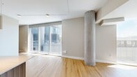 Located at 11101 NE 11th St, Unit 523 in Bellevue, WA, this contemporary single-floor condo spans 1,170 square feet and showcases a clean, modern architectural design. The open-concept living area is anchored by a striking exposed concrete column and features warm light wood flooring throughout. Floor-to-ceiling glass sliding doors flood the space with abundant natural light while offering sweeping views of the Bellevue skyline and surrounding urban landscape. The kitchen is outfitted with modern wood-grain cabinetry, a stainless steel range with a wall-mounted hood, a large center island with a white quartz countertop, and stainless steel appliances. The bathroom features light wood flooring, a wood-grain vanity with a white countertop, a glass-enclosed walk-in shower with white tile surround, and a clean, minimalist aesthetic. A dedicated laundry room provides added convenience with a full-size GE front-load washer and dryer. A standout feature of this unit is the expansive curved outdoor terrace, finished with artificial turf, glass railings, and panoramic city views — offering a rare and generous outdoor living space in an urban setting.