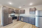 This single-floor residence offers a practical and comfortable layout across two bedrooms and two bathrooms. The combined kitchen and living area serves as the heart of the home, featuring a well-equipped kitchen with rich dark-stained cabinetry, granite-look countertops, stainless steel appliances including a range, over-the-range microwave, dishwasher, and refrigerator, all set atop light-toned hardwood-style flooring with recessed ceiling lighting throughout.

Both bedrooms are generously sized, with the primary bedroom providing a comfortable retreat. Each bedroom is finished with light hardwood-style flooring, neutral warm-toned walls, natural light from windows with blinds, and ceiling fans with integrated lighting for added comfort. The primary bedroom offers notable space for furnishing flexibility.

The two bathrooms continue the consistent design language, featuring dark wood vanities with granite-look countertops and mirrors, along with light plank-style flooring. One bathroom includes a full tub/shower combination with a clean white surround.

A dedicated laundry room houses in-unit utilities including a water heater and HVAC system, providing added convenience. A closet offers additional storage. The overall aesthetic is clean, modern, and move-in ready.