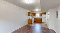 Located at 201 Chenault St in Muldraugh, Kentucky, this two-bedroom, two-bathroom apartment is thoughtfully distributed across two floors, offering a practical and comfortable layout. The main floor features a combined dining and living area with rich hardwood-style flooring that flows seamlessly throughout much of the unit. The kitchen is well-appointed with warm oak cabinetry, generous counter space, a white electric range, a refrigerator, and a double sink beneath a window that brings in natural light. Tile flooring anchors the kitchen area, providing a clean contrast to the wood floors beyond. A dedicated laundry area adds everyday convenience. Both bedrooms are bright and airy, featuring large windows that frame outdoor greenery and allow ample natural light to fill each room. The primary bedroom includes direct access to a closet, while the unit as a whole offers four closets total for generous storage. Each bathroom is clean and functional, with one featuring a full tub/shower combination and tile flooring, and the other outfitted with a wood-toned vanity and tile floors. Textured ceilings and crisp white walls lend a tidy, move-in-ready feel throughout this well-organized home.
