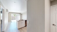 Located at 2401 Broadway Street in Vallejo, California, this one-bedroom, one-bathroom unit offers a thoughtfully designed layout across a single floor. The kitchen is a standout feature, equipped with stainless steel appliances including a refrigerator, range, and microwave, complemented by white shaker cabinetry, stone-look countertops, a deep single-basin sink, and light hardwood-style flooring. A sliding glass door in the adjacent living area connects seamlessly to a private outdoor patio, enclosed by a wood fence and offering open sky views — ideal for outdoor relaxation. The bedroom is generously proportioned, featuring plush wall-to-wall carpeting, a double-door closet, a wall-mounted mini-split AC unit, and windows that bring in natural light. The bathroom is finished with wood-look tile flooring, a glass-enclosed shower stall, and clean neutral tones throughout. A hallway connects the main spaces efficiently, contributing to the unit's practical flow. Neutral gray and beige tones used throughout the interior create a calm, cohesive aesthetic. The overall design emphasizes functionality and comfort, making this an efficient and well-appointed living space in Vallejo.