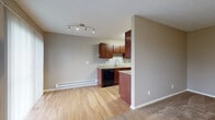 Located at 1112 Ashberry Village Dr. in Columbus, Ohio, this two-floor home offers a practical and comfortable layout spread across two levels. The main living area is generously sized, featuring warm neutral-toned walls, plush carpeting, and a sliding glass door alongside a window that invites natural light and provides outdoor views. Baseboard heating runs throughout, complemented by wall-unit air conditioning in select rooms for year-round comfort.

The kitchen is efficiently designed with rich dark-wood cabinetry, granite-style countertops, a deep undermount sink, and black appliances including a range and dishwasher. Light hardwood-style flooring grounds the kitchen space, which opens toward the living area through a half-wall peninsula. Track lighting overhead provides direct illumination.

A staircase leads to the upper level, where carpeted bedrooms offer quiet retreats. The primary bedroom includes a ceiling fan, a wall-unit AC, and a reach-in closet. Additional bedroom spaces are finished with the same neutral palette and soft carpeting. The bathroom is well-appointed with a full soaking tub and shower combination, a rich wood vanity with granite-style countertops, and wood-look flooring. Clean white trim and paneled doors carry throughout the home, providing a cohesive, tidy finish.