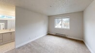 Located at 500 SW 5th Pl in Renton, WA, this well-designed three-bedroom, two-bathroom unit offers a comfortable and functional single-floor layout. The open-concept kitchen and living area serves as the heart of the home, featuring white shaker cabinetry, stainless steel appliances including a refrigerator and range, a white quartz peninsula with an undermount sink, and wood-look flooring that extends throughout the common areas. A ceiling fan overhead and a sliding glass door lead to a private balcony, bringing in natural light and outdoor views of surrounding greenery. The spacious living room transitions seamlessly between carpet and wood-look flooring, with baseboard heating and additional access to the balcony. Each bedroom is carpeted and bright, with natural light from windows and generous closet space, including a walk-in closet visible in one of the bedrooms. The bathrooms are clean and bright, featuring tile flooring with a classic mosaic pattern, a full tub/shower combo, and a vanity with white countertops. A dedicated in-unit laundry area with a full-size washer and dryer adds everyday convenience. The textured ceilings and neutral color palette throughout give the space a move-in-ready, functional character.