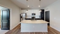 Located at 15927 White St in Charlotte, NC, this single-story home offers a thoughtfully designed open-concept layout with contemporary finishes throughout. The living area features warm wood-look flooring, recessed lighting, and pendant lights that create an inviting atmosphere. Large windows fitted with blinds allow generous natural light to fill the space, while a glass-paneled entry door enhances connectivity to the outdoors.

The kitchen serves as a central hub of the home, anchored by a substantial granite-topped island with an undermount sink and seating overhang. White shaker-style upper cabinets contrast elegantly with dark lower cabinetry, complemented by a subway tile backsplash and a full suite of stainless steel appliances, including a refrigerator with ice maker, electric range, and built-in microwave.

The bedrooms are carpeted for comfort, each featuring ceiling fans and ample natural light through blinds-equipped windows. Two bathrooms reflect the same design cohesion found throughout the home, featuring dark vanity cabinetry, granite countertops, large framed mirrors, and wood-look flooring. The primary bathroom includes a double-sink vanity, while the secondary bath offers a tub-shower combination with tiled surround.