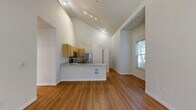 This two-story, 6-bedroom, 2-bathroom home offers a well-designed layout spread across two generously sized floors. The main level opens into a bright, airy combined kitchen and living area distinguished by dramatic vaulted ceilings and warm hardwood flooring. The kitchen features light maple cabinetry, stainless steel appliances including a refrigerator, microwave, and range, as well as a peninsula with a built-in sink and countertop seating — ideal for both cooking and casual dining. Track lighting throughout the main living area enhances the open ambiance, while a window allows natural light to fill the space. Both full bathrooms are finished consistently with light maple vanities, stone-look countertops, tub-shower combinations, and hardwood flooring. The six bedrooms are carpeted and include ceiling fans and windows that bring in natural light and outdoor views. Additional storage is available via a built-in closet with wire shelving. A dedicated laundry room houses a full-size side-by-side washer and dryer, adding everyday convenience. The home's clean, neutral palette and functional layout make it a practical and comfortable multi-bedroom residence.