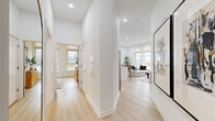 Located at 17-00 Pollitt Dr in Fair Lawn, NJ, this thoughtfully designed 2-bedroom, 2-bathroom residence offers a clean, modern aesthetic with an emphasis on natural light and open living. Light hardwood flooring flows seamlessly throughout, complementing the crisp white walls and recessed lighting that brighten every room.

The open-concept living and kitchen area serves as the heart of the home, featuring large windows on multiple walls that frame outdoor views and flood the space with daylight. The kitchen includes a white island with quartz countertops and modern cabinetry with brushed nickel hardware, opening directly to the living area for effortless entertaining.

The primary bedroom is a well-proportioned retreat with large windows, light hardwood floors, and a dedicated walk-in closet outfitted with a custom built-in organization system offering shelving, hanging rails, and drawer units. The en-suite bathroom features a sleek white vanity, undermount sink, and a frameless glass walk-in shower with tiled walls.

The second bedroom is comfortably sized with a wide window, light flooring, and a warm, neutral palette. A second full bathroom serves this room and guests, featuring a white vanity with cabinetry and a clean, minimalist design. A central hallway connects all spaces efficiently, completing this well-appointed residence.