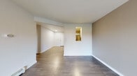 Located on Prairie Pkwy SW in Wyoming, Michigan, this single-floor unit offers a clean, modern interior with a functional and well-organized layout. The main living area features durable wood-look flooring in a warm gray tone, neutral-painted walls, and a large sliding glass door fitted with vertical blinds that floods the space with natural light while providing views of the surrounding greenery. A pass-through window connects the living area to the kitchen, enhancing the open feel between the two spaces. The kitchen is outfitted with white cabinetry, granite-style countertops, a stainless steel refrigerator, and a dishwasher, all set over matching wood-look flooring. The bedroom is carpeted for comfort and includes a window with blinds that overlooks a landscaped outdoor area, along with baseboard heating. Additional rooms include a hallway with light wood-look flooring that connects the main living spaces. The bathroom features a granite-topped white vanity, wood-look flooring, and baseboard heating, maintaining the consistent, updated aesthetic found throughout the unit. Overall, the space presents a cohesive, neutral palette with modern finishes that create a clean and comfortable living environment.