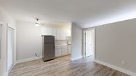 Located at 660 NE 78th St, Unit 212, in Miami's Little Haiti neighborhood, this one-bedroom, two-bathroom unit offers a clean, modern aesthetic throughout its efficiently designed single-floor layout. Wood-look laminate flooring runs continuously through the living spaces, complementing neutral gray walls and bright white trim for a fresh, cohesive look.

The combined kitchen and living area serves as the heart of the unit. The kitchen is outfitted with sleek white cabinetry extending to the ceiling, stainless steel appliances including a full-size refrigerator and gas range, and light countertops that maximize the sense of brightness. The living area is open and airy, featuring a window with vertical blinds that allows natural light to filter in.

The bedroom is a comfortable, well-proportioned space with the same wood-look flooring and neutral tones, accompanied by a dedicated closet. A wall-mounted AC unit provides climate control, and a transom window adds an additional source of natural light.

The two bathrooms are clean and well-appointed. One features a tub-shower combination with white subway tile surround, brushed gold fixtures, and a frosted window. The second bathroom showcases a modern undermount sink set in a quartz-style countertop with a frameless mirror and brushed nickel hardware, conveying a polished, updated finish throughout.