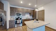 Located at 3585 SW 38th Terrace in Ocala, Florida, this single-floor residence offers a well-designed layout with contemporary finishes throughout. The kitchen serves as a standout feature, showcasing rich wood-toned cabinetry, granite countertops, a classic subway tile backsplash, and a full suite of stainless steel appliances including a refrigerator with ice maker, electric range, over-the-range microwave, and dishwasher. A central island with a matching granite surface provides additional prep space and is highlighted by a stylish pendant light above. Wood-look plank flooring flows through the kitchen and into the open living area, which is generously proportioned and filled with natural light from a large sliding glass door fitted with vertical blinds leading to an outdoor space. A ceiling fan adds comfort to the living area. The bedroom features soft, neutral carpet, a ceiling fan, and a window allowing natural light to filter in. The bathroom is appointed with wood-toned cabinetry, a granite vanity top, and consistent wood-look flooring that ties the space together. Recessed lighting and a textured ceiling throughout add to the polished, move-in-ready feel of this thoughtfully finished home.