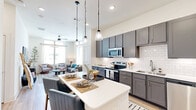 This thoughtfully designed one-bedroom, one-bathroom residence in Denton, Texas offers a cohesive open-concept layout finished with light wood-look flooring throughout. The kitchen is a standout feature, boasting gray shaker cabinetry, white subway tile backsplash, stainless steel appliances including a refrigerator, dishwasher, and electric range, plus a central island with pendant lighting—ideal for both cooking and casual dining. The kitchen flows seamlessly into the living room, which is brightened by large windows that invite abundant natural light and are topped with elevated ceilings that enhance the sense of openness. The bedroom offers a calm retreat with generous windows framing outdoor views, while a dedicated walk-in closet provides multi-tiered shelving and hanging storage. The full bathroom features dual-tone gray cabinetry with a white countertop, subway tile-lined tub/shower combination, and stylish checkered flooring. A separate laundry room accommodates a full-size washer and dryer with added overhead shelving. The overall design balances modern finishes with a warm, neutral palette, creating an inviting and functional living environment.