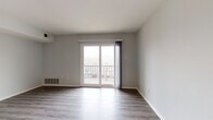 This well-appointed single-floor residence offers a clean, modern aesthetic throughout, characterized by neutral gray walls, crisp white trim, and a thoughtful layout that maximizes functionality. The open-concept living and dining area is anchored by durable light-toned hardwood-style flooring that flows seamlessly into the kitchen. Sliding glass doors lead to a private balcony, flooding the space with natural light and providing pleasant outdoor views. The kitchen is a standout feature, showcasing gray shaker-style cabinetry with gold hardware, marble-look countertops, a white subway tile backsplash, and a full suite of stainless steel appliances including a gas range, over-the-range microwave, dishwasher, and full-size refrigerator. The bedrooms are generously sized, each finished with plush wall-to-wall carpeting, ample wall space, and natural light provided by well-placed windows. One bedroom offers convenient access to a bathroom. The bathroom is finished with clean white tile flooring, a gray vanity with a white basin sink, and a framed mirror with overhead lighting. Throughout the unit, consistent attention to detail in the finishes creates a cohesive, move-in-ready living environment.