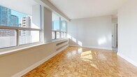 Located at 100 Roehampton Ave in Midtown Toronto, this one-bedroom, one-bathroom unit offers a well-organized layout across a single floor. The entrance opens into a functional foyer with two closets providing ample storage. Classic parquet wood flooring runs throughout the main living areas, adding warmth and character to the space.

The living room is generously proportioned, bathed in natural light through large windows that frame views of the surrounding Toronto skyline. An adjacent dining area connects seamlessly to the kitchen, which features dark cabinetry, stone-look countertops, and stainless steel appliances, including a full-size refrigerator. A private balcony extends the living space outdoors, offering a pleasant retreat with open city views.

The bedroom is a comfortable size, featuring the same parquet flooring, a sliding-door closet, and bright windows that allow natural light to fill the room. The bathroom is clean and well-appointed, with a full soaker tub and shower combination surrounded by white subway-style tiling, chrome fixtures, and white cabinetry. Throughout the unit, neutral tones, white trim, and abundant natural light create a bright, airy ambiance well-suited to urban living.