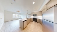 Located at 4001 198th St SW in Lynnwood, Washington, this well-appointed 2-bedroom, 2-bathroom unit offers a thoughtfully designed layout across a single floor. Light wood flooring runs seamlessly throughout the space, lending a clean, contemporary feel to every room.

The open-concept kitchen serves as a central hub, featuring flat-front cabinetry in warm neutral tones, stainless steel appliances including a refrigerator, range, microwave, and dishwasher, and a peninsula with a white quartz countertop and an undermount sink. Pendant lighting above the peninsula and recessed ceiling lights enhance both function and style.

The spacious primary bedroom offers generous proportions and is paired with a dedicated walk-in closet equipped with wire shelving on multiple walls, providing ample storage. The second bedroom is bright and well-sized, with a large window overlooking the surrounding neighborhood.

Both bathrooms feature light wood flooring, modern vanities with clean-lined cabinetry, and illuminated mirrors. The full bathroom includes a soaking tub and tiled shower surround, while the second bathroom provides a practical layout with a vanity and toilet.

Natural light is a defining characteristic, with large windows in both bedrooms offering views of the Lynnwood cityscape. The unit's neutral palette and modern finishes create a cohesive, move-in ready environment.