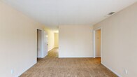 Located at 3561 Hilton Ave in Columbus, Georgia, this single-story, two-bedroom, one-bathroom home offers a practical and comfortable layout. The interior is finished with warm, neutral tones and plush carpeting throughout the main living areas and bedrooms, creating a cohesive and inviting atmosphere.

The living room is a generously sized space with clean white walls and soft carpet underfoot, connected to the rest of the home via a central hallway. The kitchen is well-equipped, featuring white cabinetry, light stone-toned countertops, tile flooring, and black appliances including a refrigerator, microwave, and dishwasher. A large window in the kitchen area brings in natural light and offers a pleasant outdoor view, complemented by a pendant light fixture above.

The primary bedroom is a comfortable, carpeted room with a ceiling fan, ample wall space, and direct access to the hallway. The second bedroom is similarly appointed with neutral carpet and bright walls. Three closets are distributed throughout the home, providing convenient storage. The bathroom is clean and functional, featuring tile flooring, a full tub-shower combination with a white surround, a vanity with storage, and warm beige walls. This home offers a straightforward, well-maintained living environment.