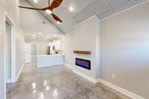Located at 211 Winter Park Pl in Duson, Louisiana, this single-story, 3-bedroom, 2-bathroom home delivers a striking blend of modern and industrial design. Polished concrete floors run throughout, reflecting light and adding a sleek, durable foundation to every room. The open-concept living and kitchen area is anchored by soaring vaulted ceilings clad in corrugated metal panels, complemented by a bold three-blade ceiling fan and recessed lighting. A wall-mounted electric fireplace with a rustic wood mantel serves as a focal point in the living space, adding warmth and character. The kitchen features white shaker cabinetry with crown molding, stainless steel appliances, a tile backsplash, and a peninsula with ample counter space. The spacious primary bedroom includes a tray ceiling with crown molding and a ceiling fan, offering an elegant retreat. Secondary bedrooms are well-sized with ceiling fans and polished concrete floors. Both bathrooms are finished with white cabinetry, quartz countertops, and brushed nickel hardware. Two generously sized closets provide abundant storage with multi-tier hanging rods and shelving. A dedicated laundry room with washer and dryer hookups completes this thoughtfully designed home.