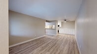 Located on E Fort Lowell Road in Tucson, Arizona, this single-story unit showcases a clean, contemporary aesthetic with a neutral color palette and thoughtfully updated finishes throughout. Light wood-look luxury vinyl plank flooring extends across the open-concept living and kitchen areas, lending warmth and visual continuity to the space.

The spacious living area is anchored by a ceiling fan and flows seamlessly toward the kitchen, which is defined by crisp white cabinetry, light quartz-style countertops, stainless steel appliances including a refrigerator and dishwasher, and a pass-through window connecting to the living space. Together, these areas create an inviting and functional hub for daily living.

Multiple bedrooms offer comfortable retreats, each featuring plush neutral carpeting and windows with blinds that bring in natural light and views of surrounding greenery. The two bathrooms are tastefully appointed: one features a full tub-shower combination with subway tile surround and wood-look flooring, while the other includes a white vanity with a stone-topped sink, a large mirror, louvered closet doors, and matching flooring. The overall ambiance is fresh, understated, and move-in ready.