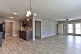 Located at Reservoir Dr in Canton, GA, this single-floor residence offers a well-designed layout with a clean, modern aesthetic. Light-toned hardwood-style flooring flows consistently throughout the space, complemented by neutral gray walls and crisp white baseboards and trim with elegant crown molding accents in the hallway.

The open living area is bright and generously proportioned, featuring a ceiling fan, large windows dressed with blinds, and glass French doors that lead to an outdoor balcony, allowing natural light to fill the room. Adjacent to the living space, a dedicated dining area is highlighted by a classic multi-arm chandelier, creating an inviting atmosphere for meals.

The galley-style kitchen is well-equipped, featuring rich dark cabinetry with modern hardware, granite-style countertops, a tile backsplash, a deep double-basin sink, and black appliances including a range and refrigerator. A walk-in pantry with built-in shelving provides ample storage.

The hallway connects the living areas to the private rooms via interior doors, maintaining a tidy flow throughout. The bathroom is a standout feature, offering a soaking tub with full tile surround, dark cabinetry with a granite-topped vanity, and wood-look flooring. A bedroom with carpet flooring adds warmth and comfort to the private quarters of the home.