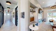 Located at 1800 Slaughter Rd in Huntsville, Alabama, this thoughtfully designed community clubhouse spans a generous single floor, offering a diverse range of amenities for residents. The welcoming entrance foyer greets visitors with light wood-look flooring, a statement ring chandelier, French doors flooding the space with natural light, and curated artwork that sets an inviting tone throughout.

The lounge area serves as the heart of the clubhouse, featuring a linear fireplace flanked by built-in shiplap shelving niches, comfortable seating in rich jewel tones, and a dramatic chandelier overhead. Large sliding glass doors provide views and access to an outdoor area. Adjacent to the lounge is a glass-enclosed conference room outfitted with a wooden table, upholstered chairs, and pendant lighting — ideal for meetings or collaborative work.

Private study nooks with built-in desks, wall sconces, and large windows overlooking lush green grounds offer quiet, focused workspaces. A café-style refreshment station features sage green cabinetry, a white countertop, and stylish décor accents.

The fitness center is well-equipped with cardio machines, strength equipment, floor-to-ceiling mirrors, large ceiling fans, and a distinctive checkered tile floor — with windows offering views of the pool area. Throughout, the design blends modern farmhouse aesthetics with contemporary finishes, creating a polished and functional community gathering space.