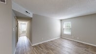 Located at 1 Bosquet Ct in Summerville, South Carolina, this single-floor residence offers a clean, functional layout with consistent neutral gray tones and white trim throughout. The living area greets you at entry with warm wood-look luxury vinyl flooring, a textured ceiling, and a bright window fitted with blinds that allow natural light to filter in. The space flows into a dedicated dining area, distinguished by its own pendant light fixture and an additional window, creating a well-lit spot for everyday use. The kitchen features white cabinetry, stone-patterned countertops, and stainless appliances including a range and refrigerator, all set over matching wood-look flooring. The bedroom is generously proportioned, finished with plush neutral carpeting, and benefits from dual windows on two walls that invite ample natural light. A standout feature of the bedroom is the pair of side-by-side closets with louvered bi-fold doors, each equipped with built-in shelving and hanging rods for organized storage. The bathroom includes a full tub-shower combination with clean white surround. Textured ceilings are consistent throughout the home, and the overall palette of soft grays, crisp white trim, and warm flooring tones creates a cohesive, move-in-ready environment.