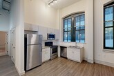 Located at 923 Locust St in downtown St. Louis, this 2-bedroom, 2-bathroom unit showcases a compelling blend of historic architectural character and modern finishes. Dramatic soaring ceilings carry throughout the space, lending an open and airy atmosphere that feels notably generous despite its efficient footprint.

The kitchen is a standout feature, boasting stainless steel appliances — including a refrigerator, range, microwave, and dishwasher — paired with crisp white cabinetry, granite countertops, and a classic white tile backsplash. A striking arched window with dark steel framing floods the kitchen with natural light and adds to the building's historic charm. Hardwood-style flooring runs throughout the main living areas.

Both bedrooms are carpeted for comfort and feature large windows with the same bold steel framing, offering views of the surrounding urban environment. The primary bedroom includes a closet with built-in shelving. Each bathroom is well-appointed with floating vanities, granite countertops, and hardwood-style flooring. Industrial-style lighting accents the hallways, adding a modern edge. The layout also includes a dedicated entrance and closet, providing practical storage and a smooth flow throughout the unit.