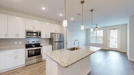 Located at 700 City View Loop in Midlothian, VA, this well-appointed 2-bedroom, 2-bathroom residence offers a thoughtfully designed single-floor layout. The open-concept kitchen and living area serves as the heart of the home, anchored by a central island with granite countertops, an integrated sink, and stylish pendant lighting overhead. White shaker cabinetry, a subway tile backsplash, and a full suite of stainless steel appliances — including a refrigerator, range, and microwave — complete the kitchen. Wood-style plank flooring flows throughout the main living areas, while a ceiling fan and large windows bring natural light and outdoor views into the living room, which also features access to a private balcony. The spacious primary bedroom is carpeted for comfort, includes a ceiling fan, and connects to a dedicated closet and an en-suite bathroom featuring a granite-topped vanity, walk-in shower with glass enclosure, and wood-style flooring. The second bedroom is equally well-lit with a large window and ceiling fan. The second bathroom mirrors the same refined finishes, offering a granite vanity and a tub-shower combination. Two hallways and additional closets provide ample storage throughout this clean, modern residence.
