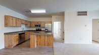 This single-floor residence offers a thoughtfully designed open-concept layout that connects the kitchen and living areas into one cohesive, functional space. The kitchen is a standout feature, showcasing natural knotty wood cabinetry, dark granite-style countertops, and a full suite of stainless steel appliances, including a French door refrigerator with ice maker, electric range, built-in microwave, and dishwasher. A central island with matching wood paneling and countertop provides additional workspace and storage. Wood-look plank flooring runs throughout the kitchen and entry areas, transitioning into plush neutral carpet in the living and bedroom spaces.

The living area is bright and open, benefiting from a sliding glass door that admits natural light and provides outdoor access. A ceiling fan and chandelier-style light fixture add character to the space. The bedrooms are carpeted and feature windows with blinds. The bathrooms are finished with wood-toned vanity cabinetry, granite-style countertops, wood-look flooring, and a tub-shower combination. Throughout the unit, the clean, neutral palette and consistent use of natural wood tones create a warm, cohesive ambiance.