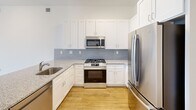 This well-appointed 3-bedroom, 2-bathroom residence at 250 Celebration Ct in Middletown, Delaware offers a thoughtfully designed single-floor layout with modern finishes throughout. Warm hardwood-style flooring runs continuously across the space, complemented by clean white walls and crisp shaker-style doors that lend a cohesive, contemporary aesthetic.

The open-concept kitchen and living area serves as the heart of the home. The kitchen features granite countertops, a center island with an integrated sink, white shaker cabinetry, stainless steel appliances including a French door refrigerator, and a tasteful tile backsplash. The adjacent living area is bathed in natural light through large floor-to-ceiling windows that frame expansive outdoor views and are fitted with roller shades.

The generously sized primary bedroom continues the theme of natural light with oversized windows and includes a dedicated walk-in closet outfitted with built-in shelving. Each bedroom is equipped with a ceiling fan for year-round comfort. The bathrooms are finished with granite vanity tops, white cabinetry, and a marble-accented tub surround. A dedicated laundry area houses a stacked Electrolux washer and dryer unit. A welcoming hallway connects all rooms, completing this clean and functional layout.