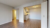 Located at 203 Burningtree Cir in Independence, MO, this single-floor, one-bedroom, one-bathroom residence offers a practical and functional layout. The living room is bright and airy, featuring wood-style vinyl flooring and a sliding glass door fitted with vertical blinds that allows ample natural light to flow into the space. The kitchen is semi-open to the living area, separated by a half-wall peninsula with a granite-style countertop that provides additional prep space. White cabinetry lines the kitchen walls, complemented by black appliances including a refrigerator and electric range, along with an under-cabinet range hood and a stainless steel sink. A hallway connects the main living area to the bedroom and bathroom. The spacious bedroom is carpeted for comfort and includes a closet, a window with blinds for natural light, and neutral-toned walls. The bathroom features a white vanity with a granite-style countertop, a mirror cabinet, tile-surround bathtub, and wood-style flooring that carries through from the rest of the unit. The entry foyer includes a closet for additional storage. Neutral gray tones, textured ceilings, and consistent finishes throughout lend the space a clean, cohesive appearance.