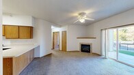 Located in Iowa City, Iowa, this single-floor residence offers a thoughtfully laid-out living space with a clean, functional design throughout. The living room serves as the centerpiece of the home, featuring plush wall-to-wall carpeting, a tile-surround gas fireplace with a wood mantel, and a ceiling fan with overhead lighting. A sliding glass door opens directly to a private patio, allowing natural light to fill the space and providing easy outdoor access. A built-in desk area adds practical functionality to the living space. The kitchen is well-appointed with warm oak cabinetry offering generous upper and lower storage, white countertops, a double-basin stainless steel sink, and a dishwasher. The bedrooms are carpeted and offer ample space, with at least one room featuring a full-width bi-fold closet with wood-framed doors for organized storage. The bathroom is finished with neutral tile flooring and includes a full-size soaking tub and shower combination with chrome fixtures. White walls and warm wood trim are consistent throughout, creating a cohesive and understated aesthetic. The textured ceilings and neutral color palette provide a versatile backdrop suited to a variety of interior styles.