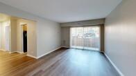 Located at 2401 Arlington Blvd in Charlottesville, VA, this one-bedroom, one-bathroom unit offers a practical and well-organized single-floor layout. The living room is a standout feature, with wood-style plank flooring, neutral walls, and a large sliding glass door fitted with vertical blinds that floods the space with natural light and provides direct outdoor views. The galley-style kitchen is efficiently arranged, featuring warm oak cabinetry, dark granite-style countertops, a stainless steel sink, and black appliances including a range and refrigerator. A ceiling fan overhead adds to the functional design, and the kitchen opens conveniently toward the living area. The bedroom is a comfortable, well-proportioned room with soft carpeting, a window with blinds offering outdoor views, and easy access to the closet. The full bathroom is thoughtfully appointed with a tub-shower combination, a wood-framed vanity mirror with overhead lighting, an oak vanity cabinet, and a white countertop sink. Wood-style flooring continues in the bathroom, providing a cohesive aesthetic throughout the unit. A dedicated closet rounds out the layout, providing practical storage. Clean lines, neutral tones, and functional finishes define the overall character of this Charlottesville residence.