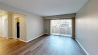 Located at 2401 Arlington Blvd in Charlottesville, VA, this one-bedroom, one-bathroom unit offers a practical and well-organized single-floor layout. The living room is a standout feature, with wood-style plank flooring, neutral walls, and a large sliding glass door fitted with vertical blinds that floods the space with natural light and provides direct outdoor views. The galley-style kitchen is efficiently arranged, featuring warm oak cabinetry, dark granite-style countertops, a stainless steel sink, and black appliances including a range and refrigerator. A ceiling fan overhead adds to the functional design, and the kitchen opens conveniently toward the living area. The bedroom is a comfortable, well-proportioned room with soft carpeting, a window with blinds offering outdoor views, and easy access to the closet. The full bathroom is thoughtfully appointed with a tub-shower combination, a wood-framed vanity mirror with overhead lighting, an oak vanity cabinet, and a white countertop sink. Wood-style flooring continues in the bathroom, providing a cohesive aesthetic throughout the unit. A dedicated closet rounds out the layout, providing practical storage. Clean lines, neutral tones, and functional finishes define the overall character of this Charlottesville residence.