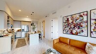 Located at 17071 W Dixie Hwy in North Miami Beach, FL, this well-appointed 2-bedroom, 2-bathroom residence offers a thoughtfully designed open-concept layout finished with contemporary details throughout. Marble-look tile flooring flows seamlessly across the entire space, enhancing the bright, clean aesthetic.

The kitchen is a standout feature, showcasing granite countertops, a central island with pendant lighting, two-tone cabinetry combining white uppers with warm wood-grain lowers, stainless steel appliances, and open shelving for added functionality. It opens directly into the combined dining and living area, creating an inviting, connected atmosphere ideal for entertaining.

The living room is bathed in natural light from expansive floor-to-ceiling sliding glass doors that lead to a balcony with scenic outdoor views of the surrounding greenery. A ceiling fan and bold abstract artwork lend character to the space.

Both bedrooms are generously proportioned, each featuring large windows with balcony access and ample natural light. The primary bedroom connects to a dedicated walk-in closet and a private en-suite bathroom complete with granite dual vanity, a glass-enclosed walk-in shower, and refined black hardware accents. Two closets provide excellent storage throughout the residence.