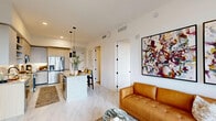 Located at 17071 W Dixie Hwy in North Miami Beach, FL, this well-appointed 2-bedroom, 2-bathroom residence offers a thoughtfully designed open-concept layout finished with contemporary details throughout. Marble-look tile flooring flows seamlessly across the entire space, enhancing the bright, clean aesthetic.

The kitchen is a standout feature, showcasing granite countertops, a central island with pendant lighting, two-tone cabinetry combining white uppers with warm wood-grain lowers, stainless steel appliances, and open shelving for added functionality. It opens directly into the combined dining and living area, creating an inviting, connected atmosphere ideal for entertaining.

The living room is bathed in natural light from expansive floor-to-ceiling sliding glass doors that lead to a balcony with scenic outdoor views of the surrounding greenery. A ceiling fan and bold abstract artwork lend character to the space.

Both bedrooms are generously proportioned, each featuring large windows with balcony access and ample natural light. The primary bedroom connects to a dedicated walk-in closet and a private en-suite bathroom complete with granite dual vanity, a glass-enclosed walk-in shower, and refined black hardware accents. Two closets provide excellent storage throughout the residence.