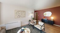 Located at 4800 Berwyn House Rd in College Park, MD, this well-appointed 2-bedroom, 1-bathroom unit offers a thoughtfully designed single-floor layout with modern finishes throughout. Light wood flooring flows continuously across the living, dining, kitchen, and bedroom areas, creating a cohesive and airy feel.

The open-concept living room is bright and welcoming, featuring large sliding glass doors that lead to an outdoor patio, flooding the space with natural light and providing direct views of lush greenery. A second window further enhances the room's brightness. Accent walls in muted rose and deep red tones add character without overwhelming the clean, neutral palette.

The kitchen is well-equipped with stainless steel appliances, including a gas range, dishwasher, and refrigerator. Two-tone cabinetry — white uppers and warm wood lowers — pairs with grey quartz countertops and a textured tile backsplash for a contemporary look.

The spacious primary bedroom features dual windows with outdoor views, generous closet space with sliding doors, and a calm, neutral atmosphere ideal for rest. The second bedroom is equally comfortable, with a built-in closet and ample room for a desk and workspace.

The bathroom is finished with floor-to-ceiling vertical tile in the walk-in glass shower, complemented by mosaic tile flooring and elegant vanity lighting.